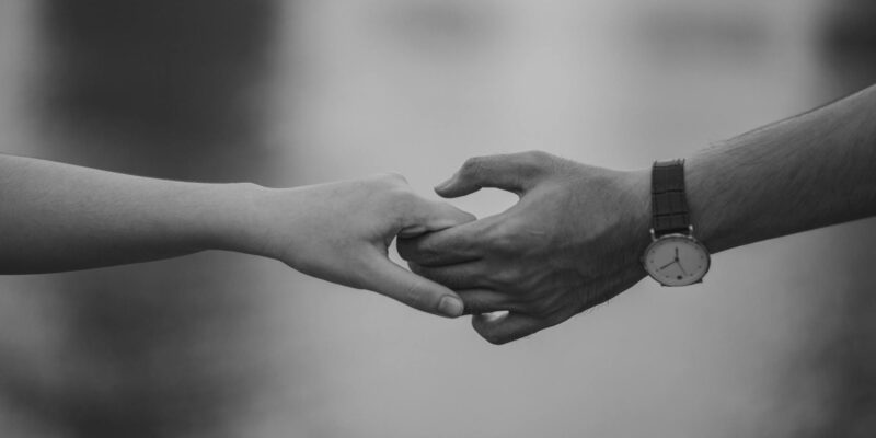 monochrome photo of couple holding hands