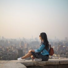 woman sitting on top of building s edge